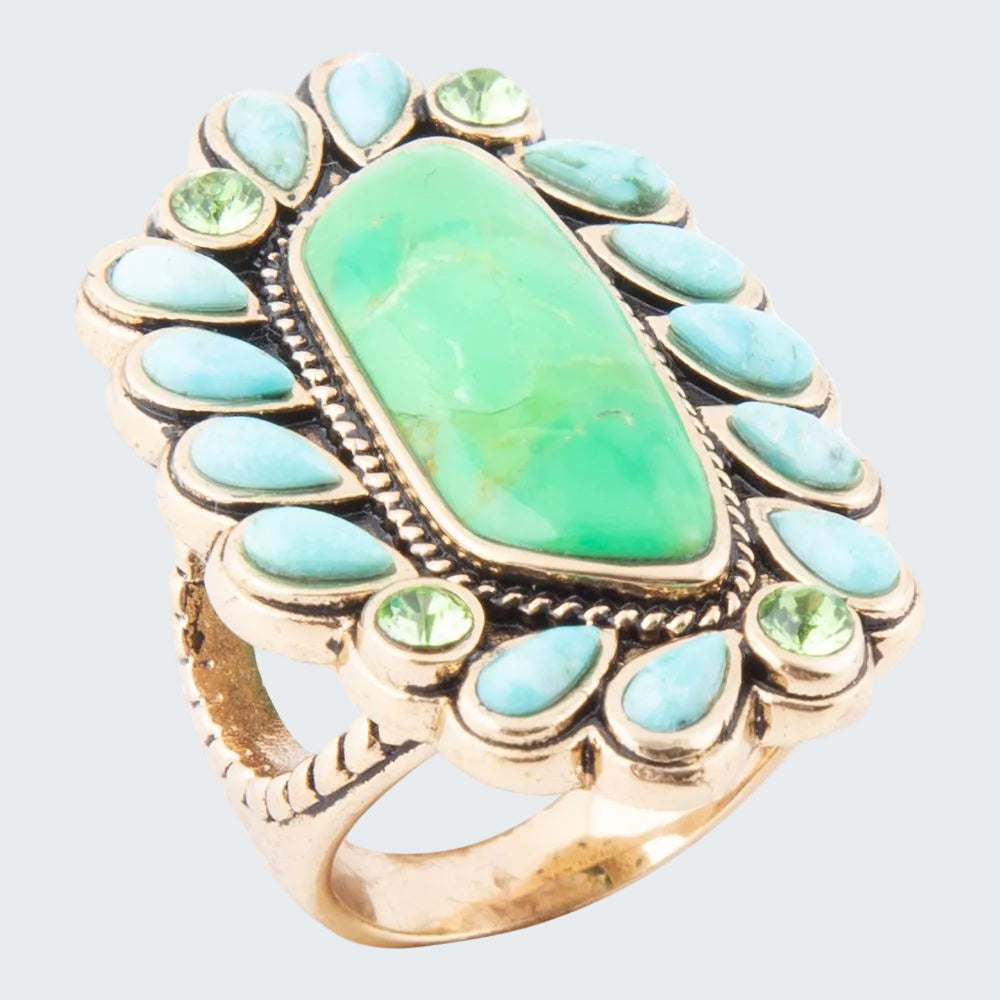 Gold ring with a large green stone and smaller turquoise stones on a white background
