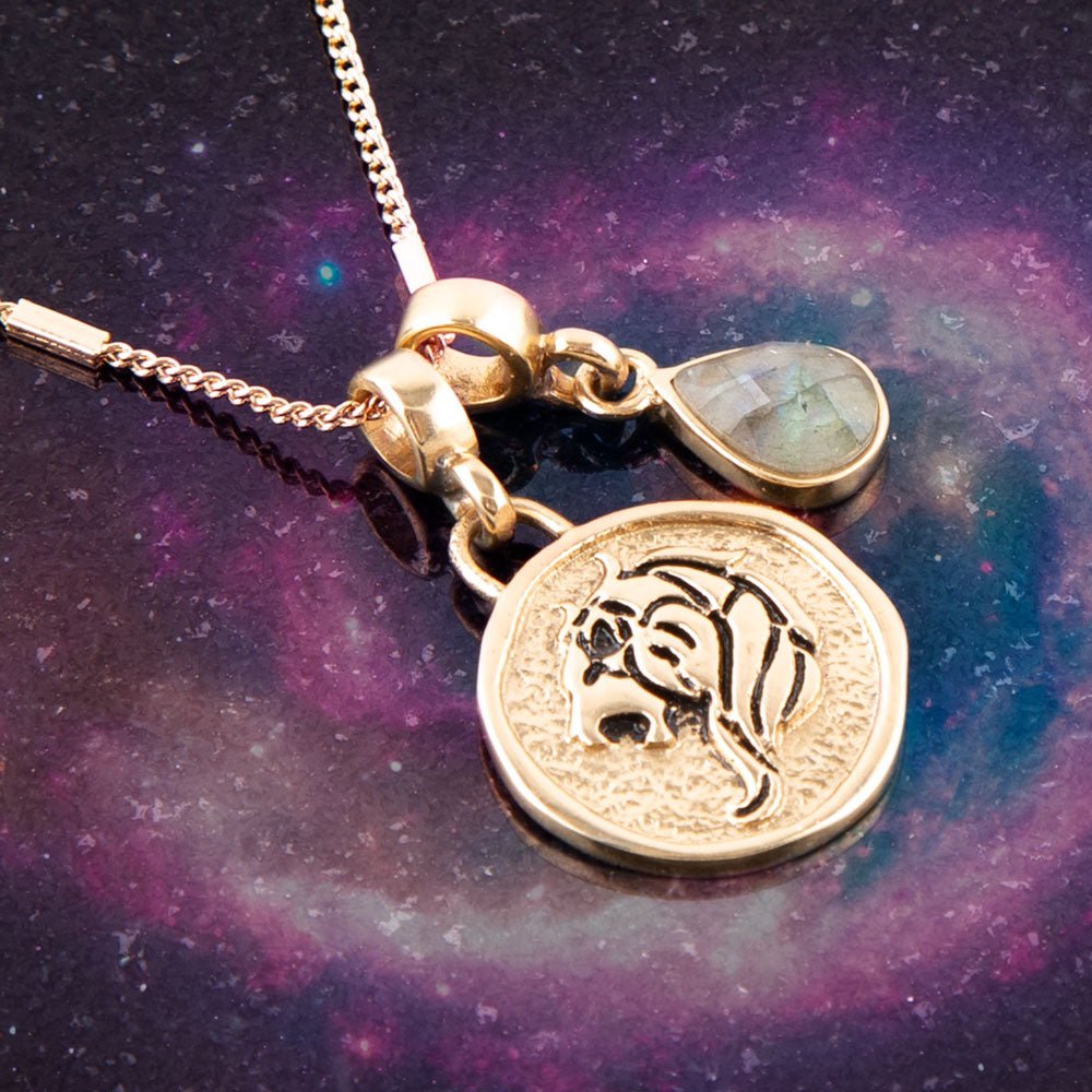 Gold necklace with a zodiac pendant on a purple and blue gradient background