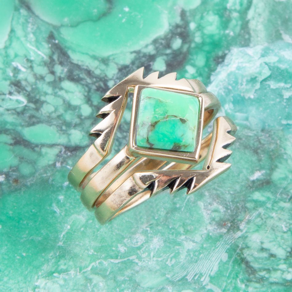 Gold ring with a green stone on a green marbled background