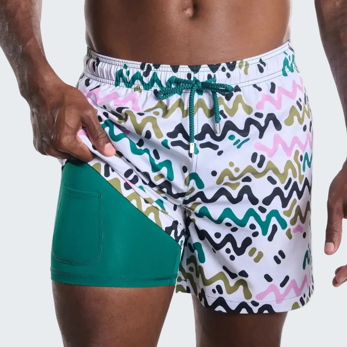 Person wearing a colorful patterned swim shorts with a green inner lining on a white background