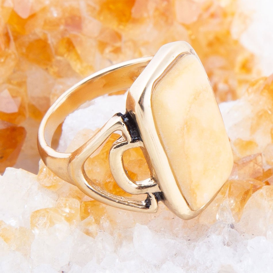 Gold ring with a unique design on a textured orange and white background