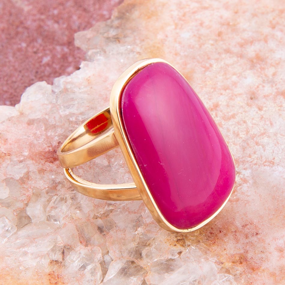 Gold ring with a pink stone on a textured pink background