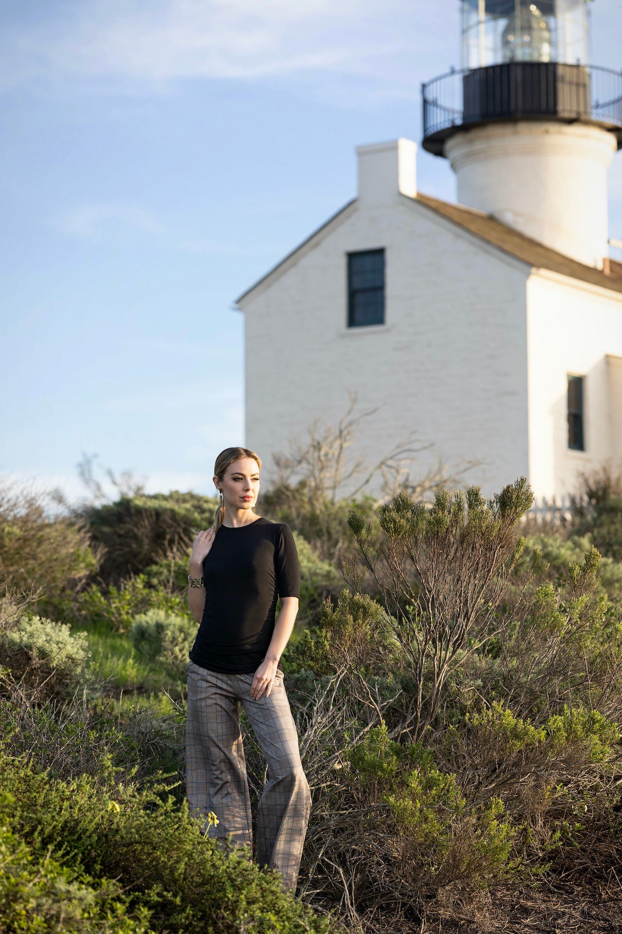 Person standing in front of a lighthouse with a clear sky