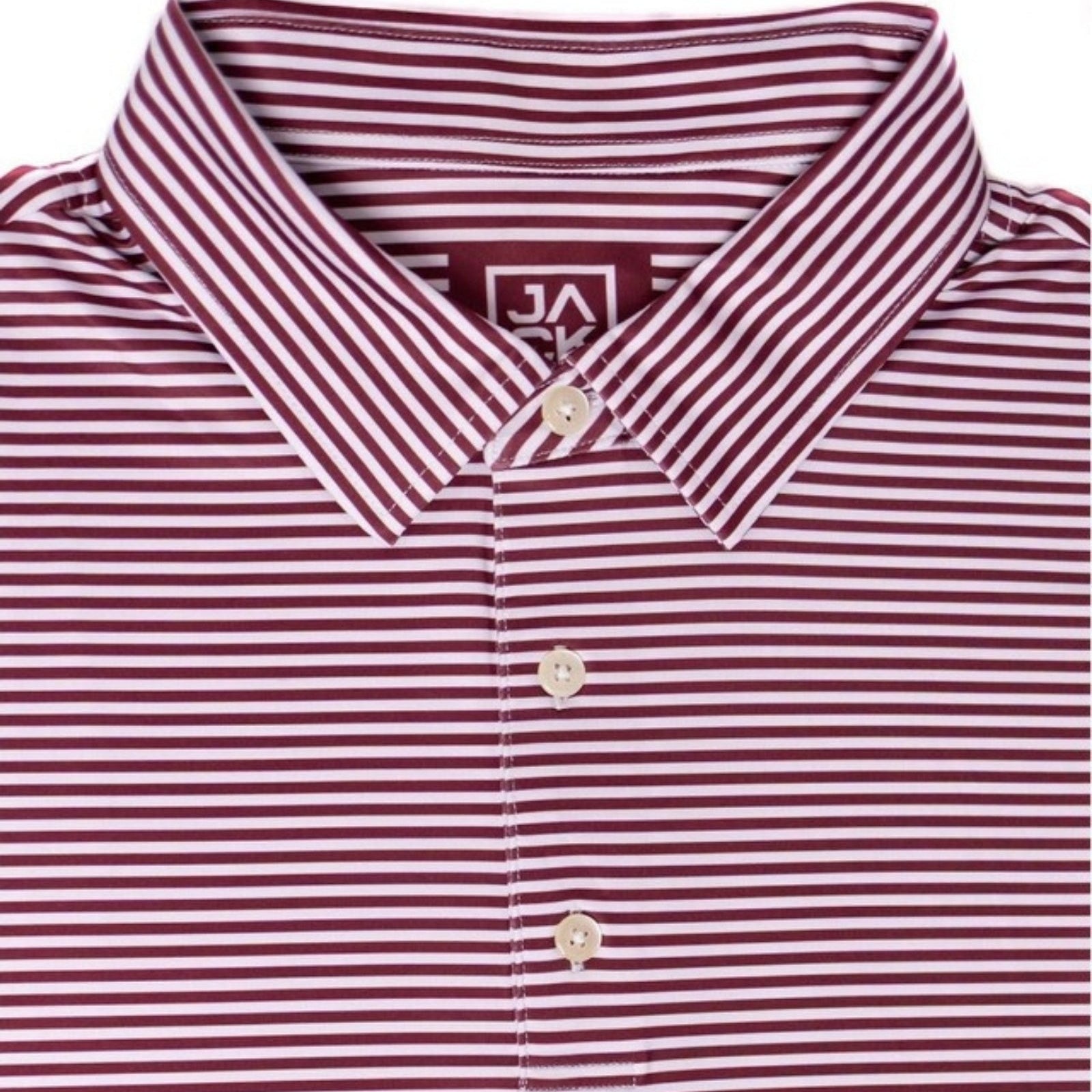 A close-up of a collared button-up shirt with thin horizontal burgundy and white stripes, featuring a pointed collar and light-colored buttons. A brand label reading 'JA' is visible inside the collar.