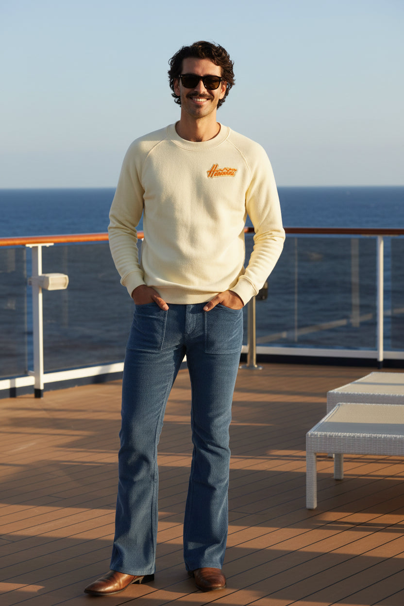 Man wearing a light-colored sweater and blue jeans on a white background