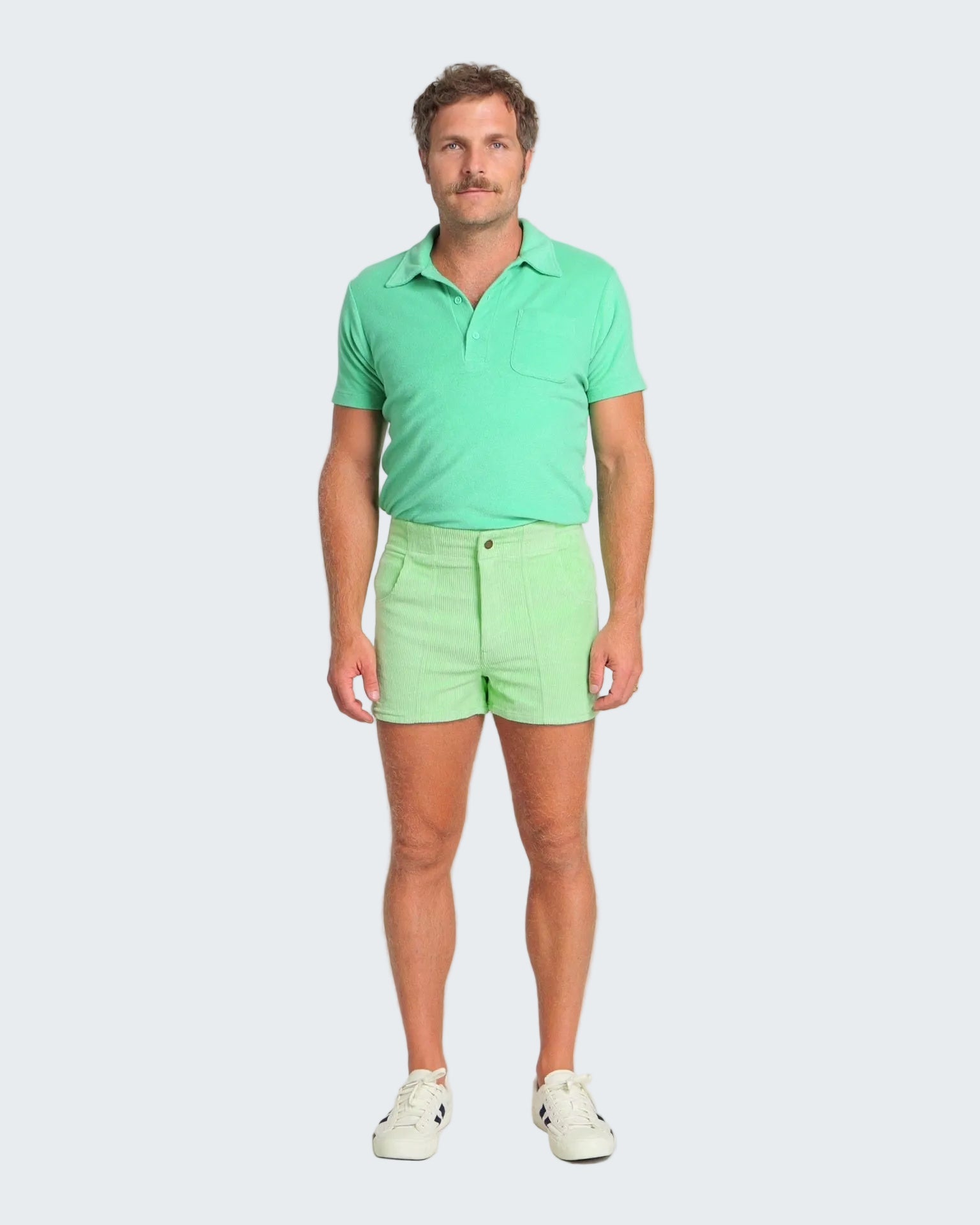 Man wearing a green polo shirt and shorts on a white background
