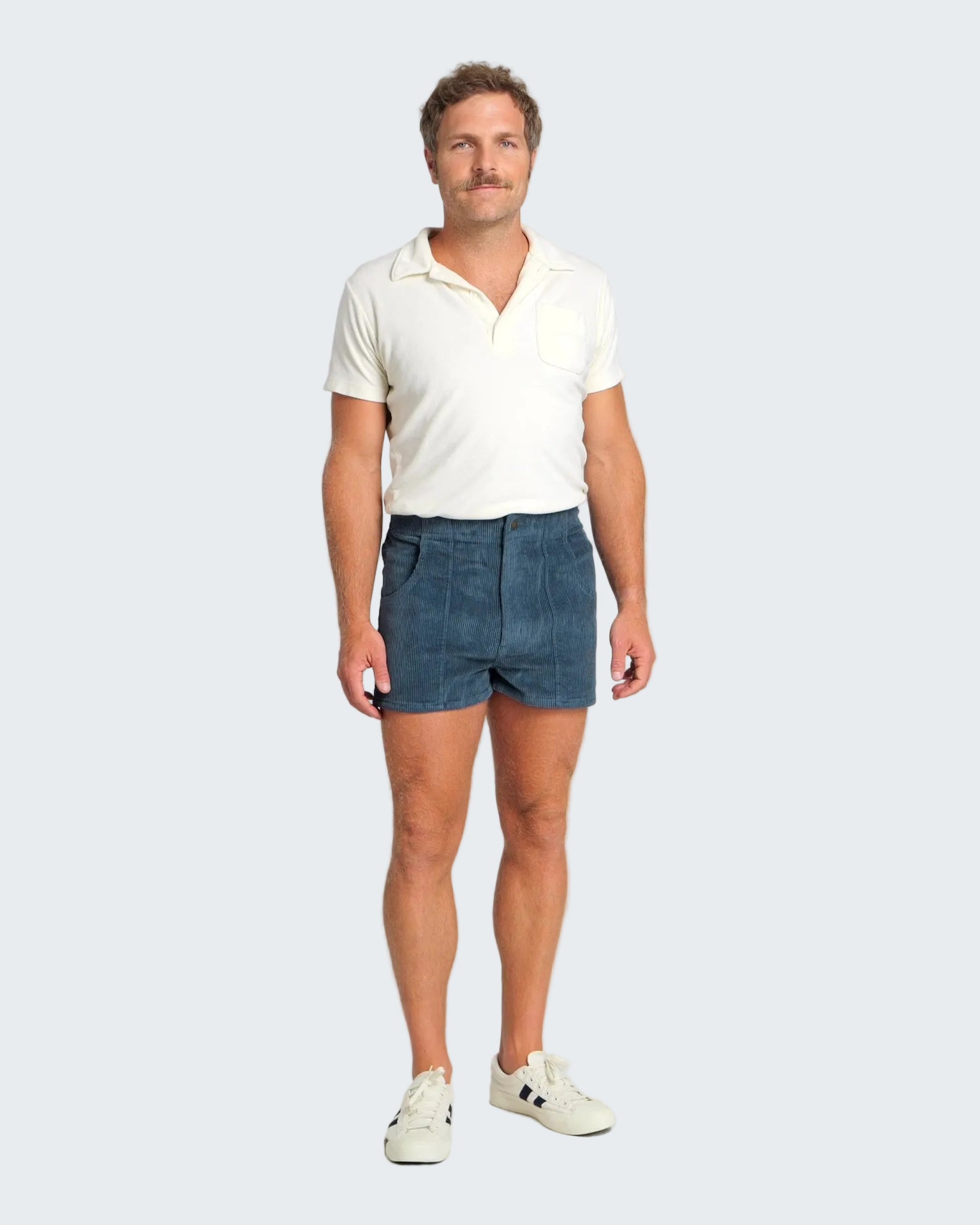 Man wearing a white polo shirt and blue shorts on a plain background
