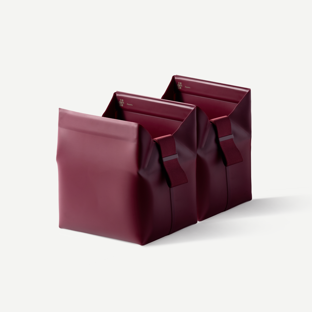 Two maroon leather bags stacked on a light gray background