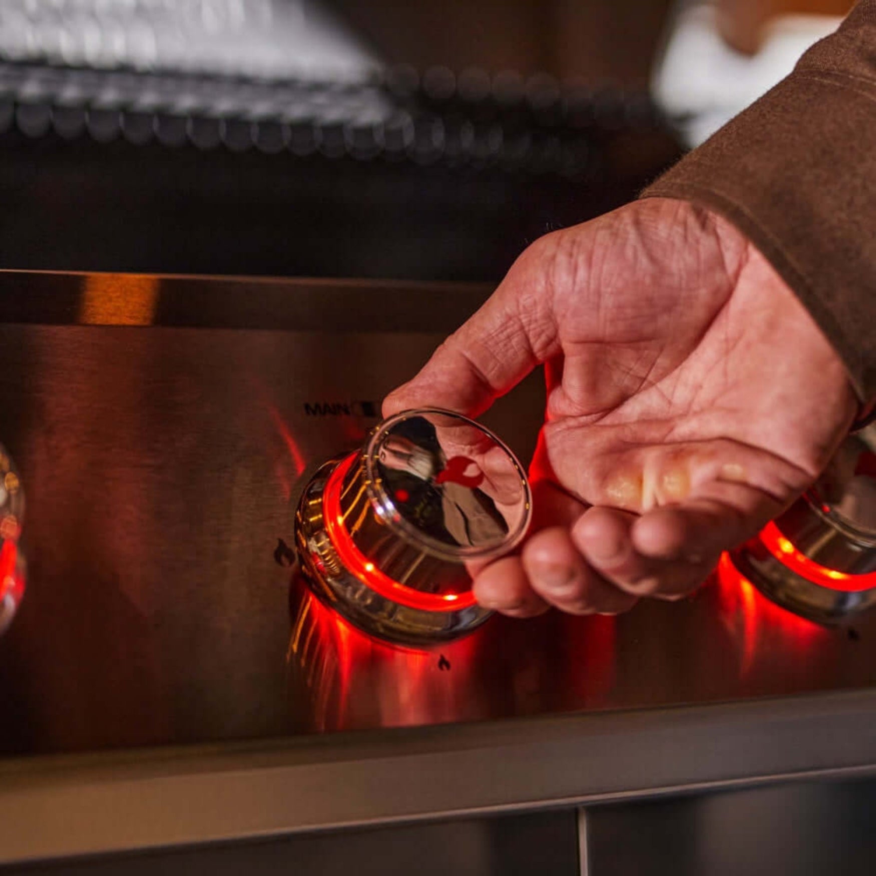 Person adjusting a stove knob with a close-up view