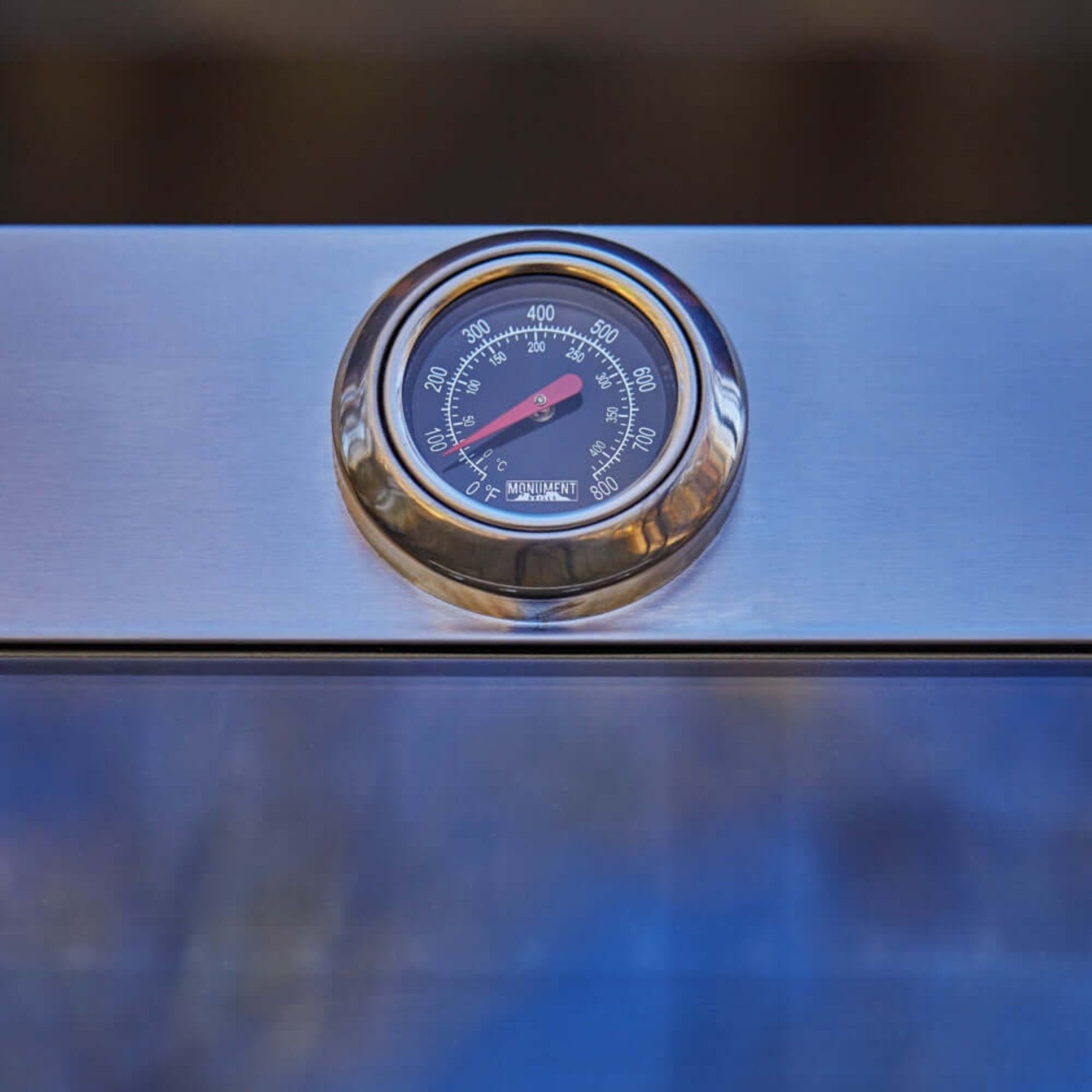 Temperature gauge on a grill with a blurred background