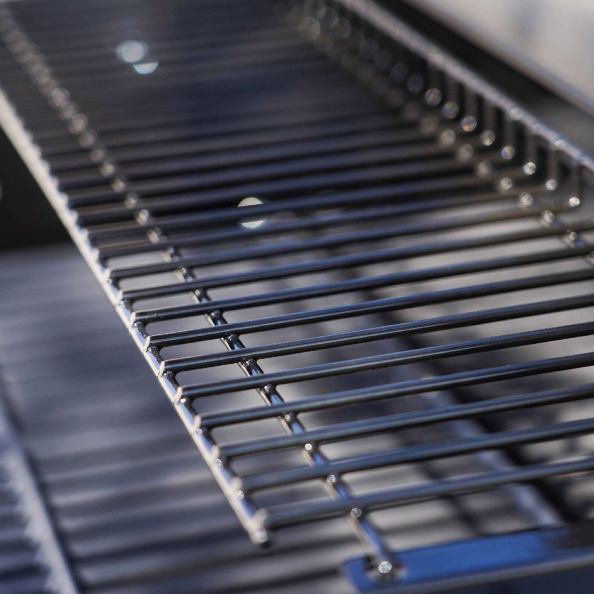 Close-up of a metal grill grate on a blurred background