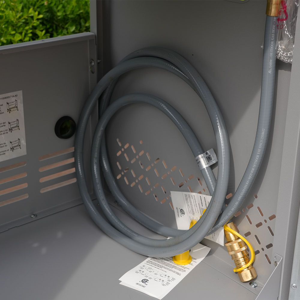 Gray hose with a brass fitting attached to a metal box with labels.