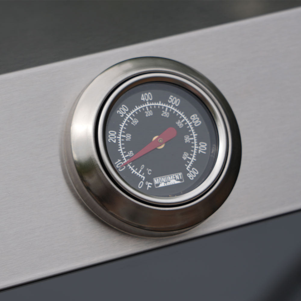 Temperature gauge on a grill with a visible brand logo.