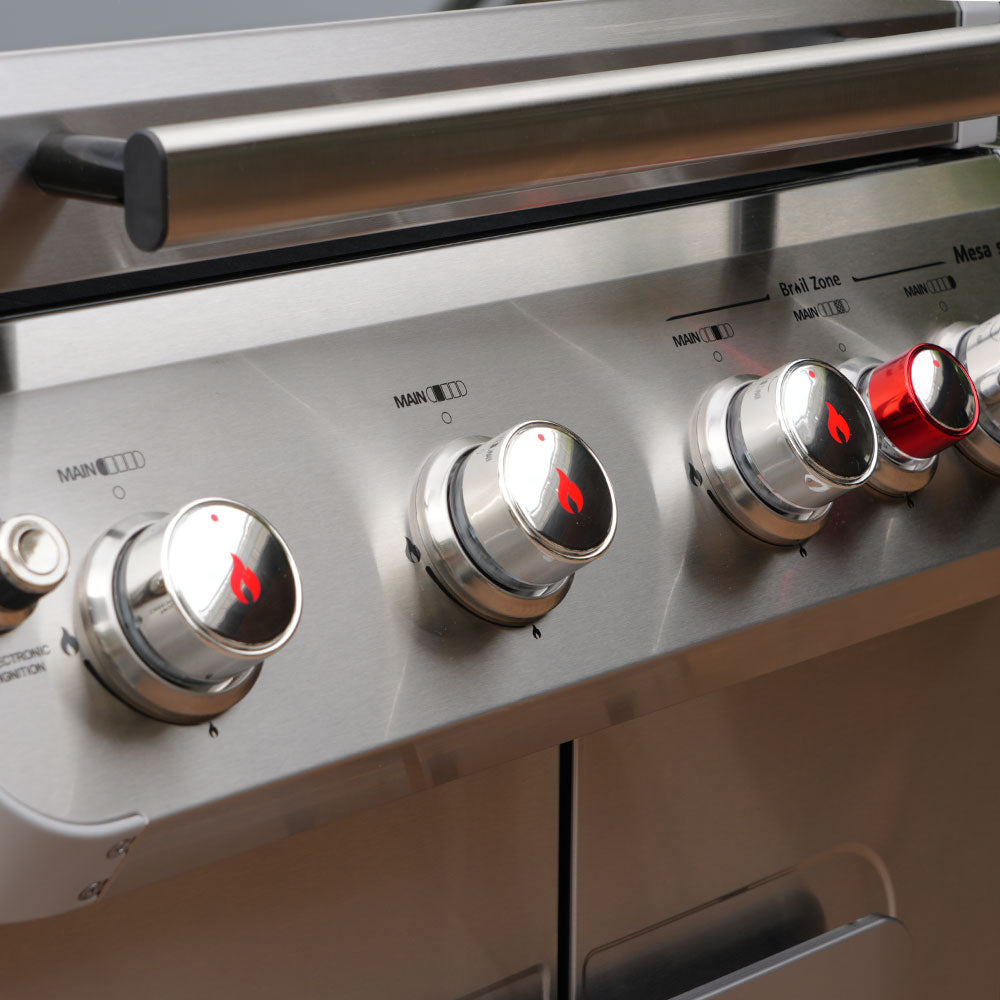 Close-up of a gas grill with control knobs on a blurred background