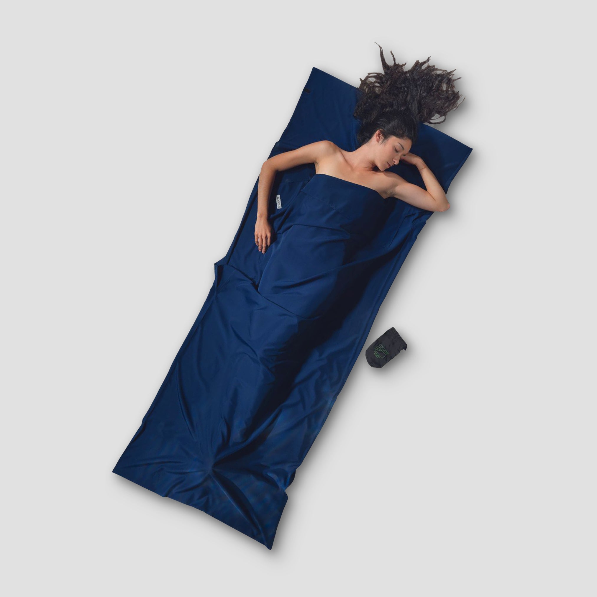 Woman lying on a blue sleeping bag with a white background