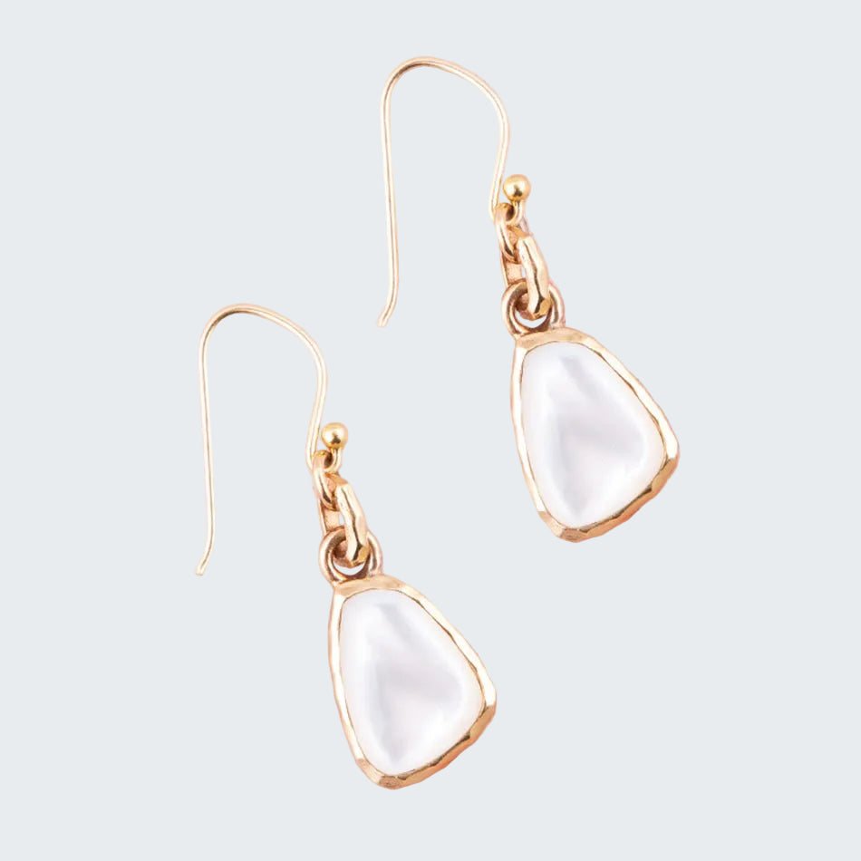 Gold earrings with white stones on a pink background