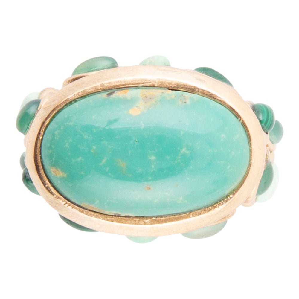 Ring with a large green stone and gold accents on a white background