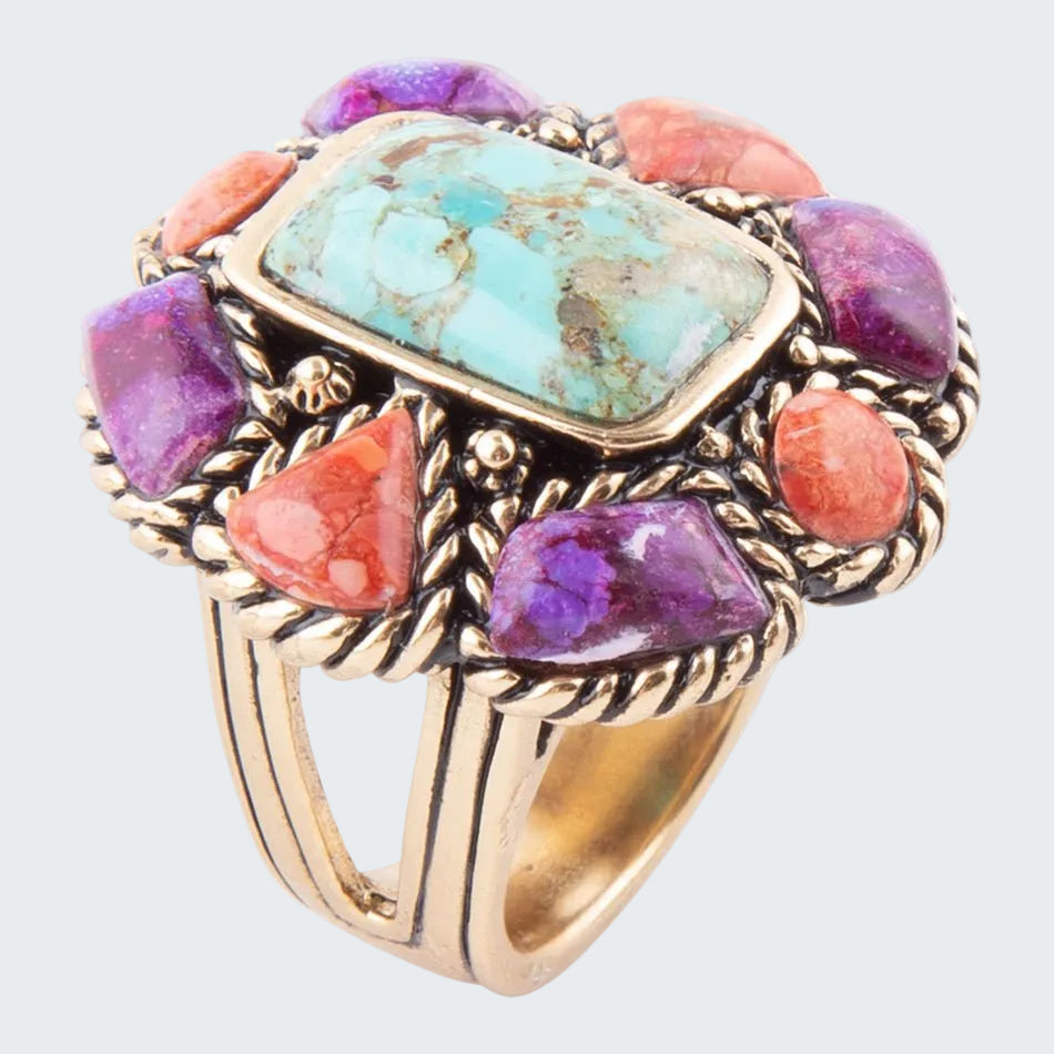 Gold ring with turquoise, purple, and coral stones on a white background