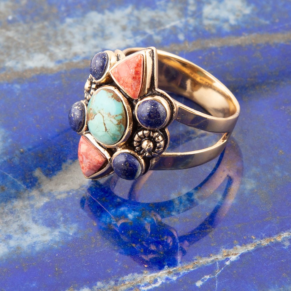 Decorative ring with colorful stones on a blue textured surface