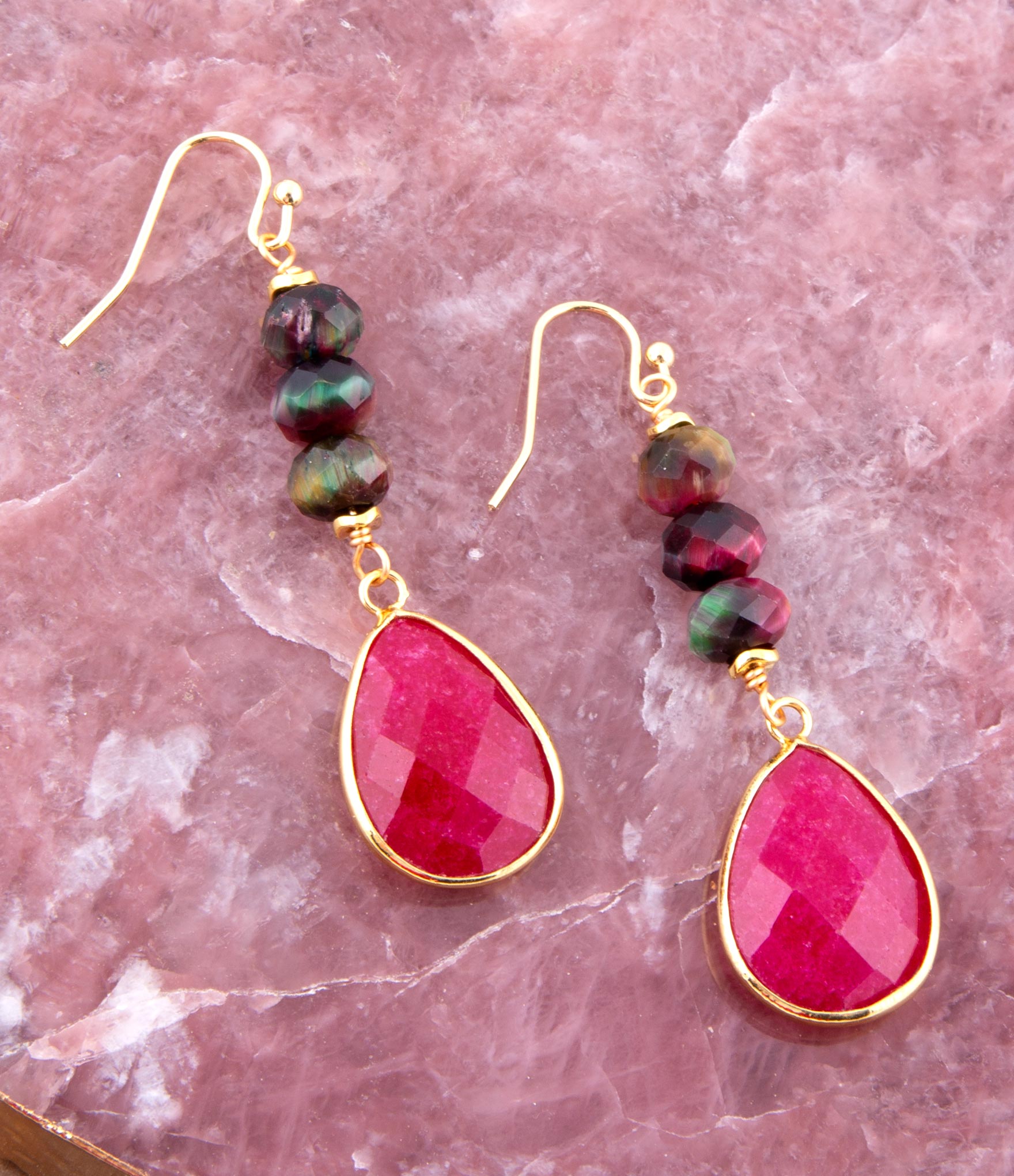 Pink teardrop earrings with gold accents on a pink marble background