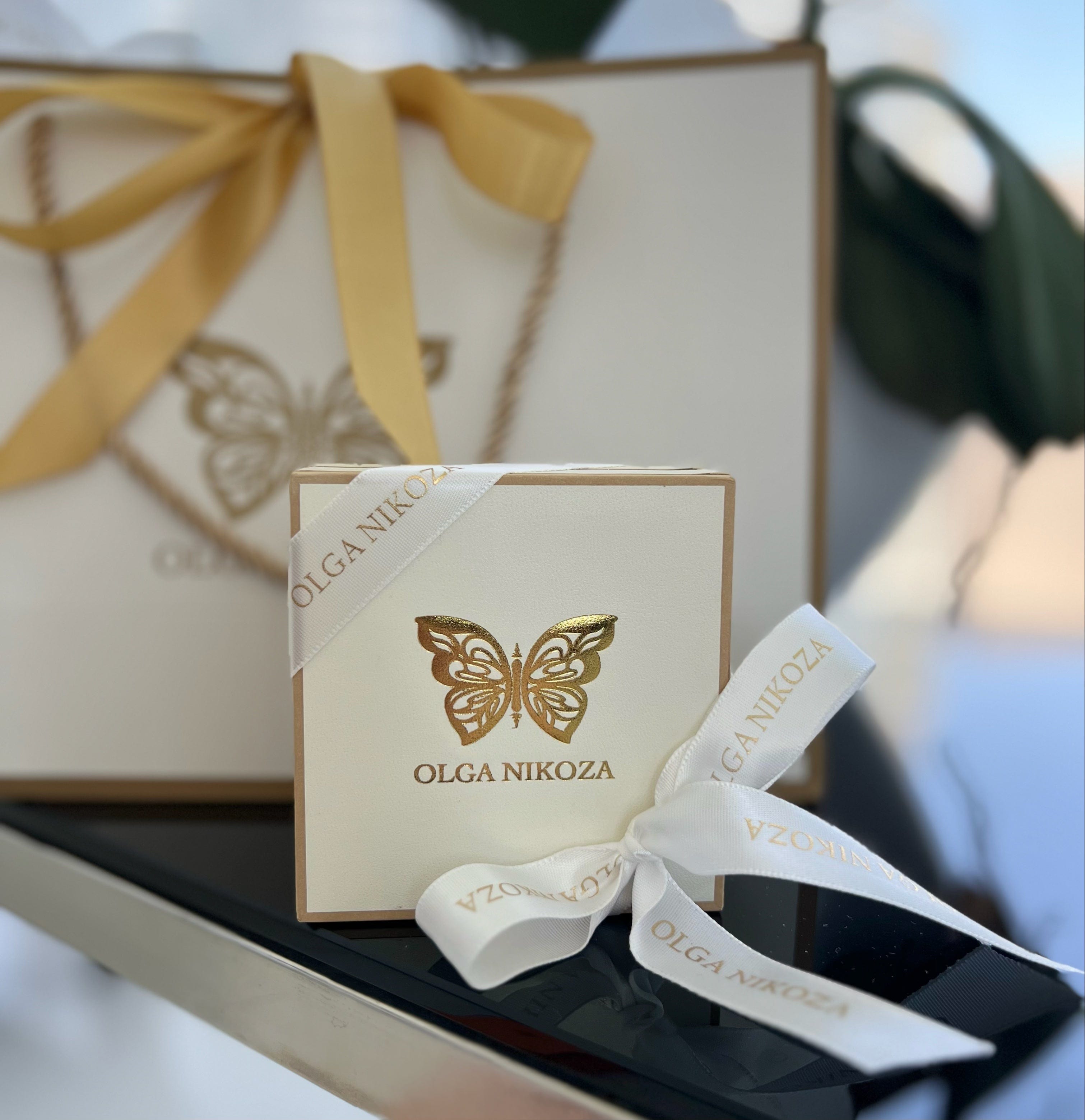 Small box with a butterfly logo and 'Olga Nikoza' branding, tied with a ribbon.