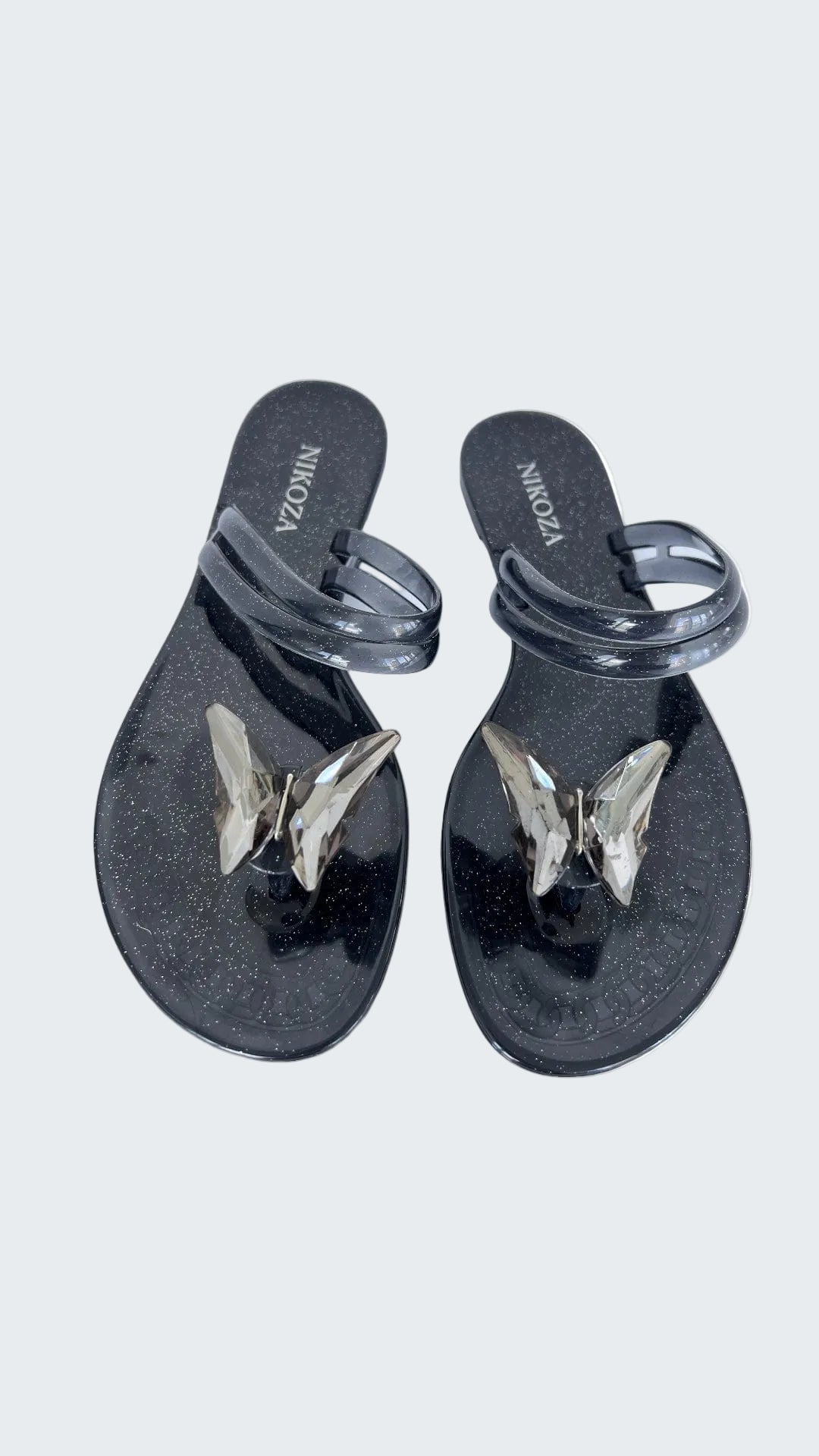 Black sandals with butterfly designs on a white background