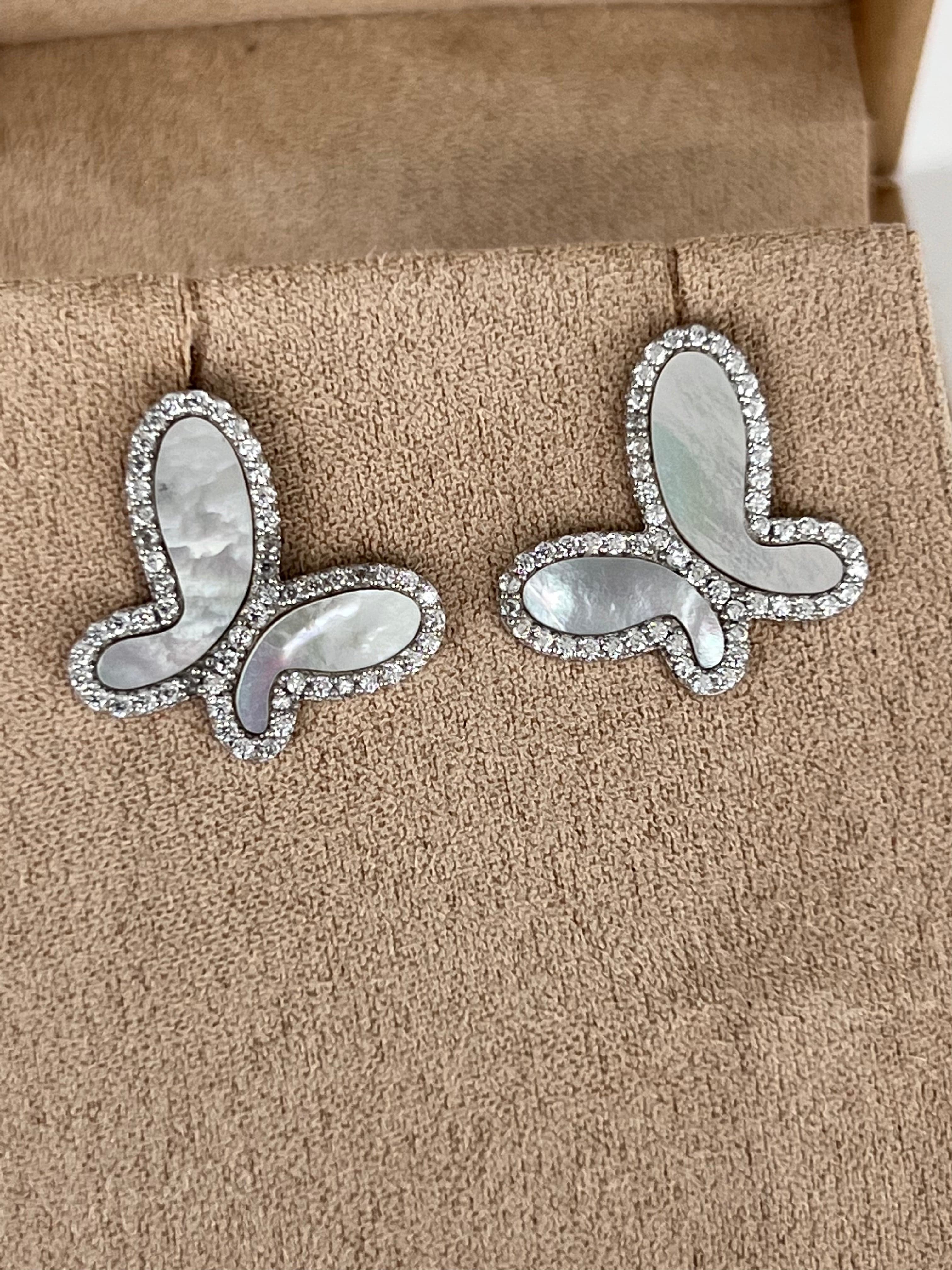 Butterfly-shaped earrings with gemstones on a brown cushion