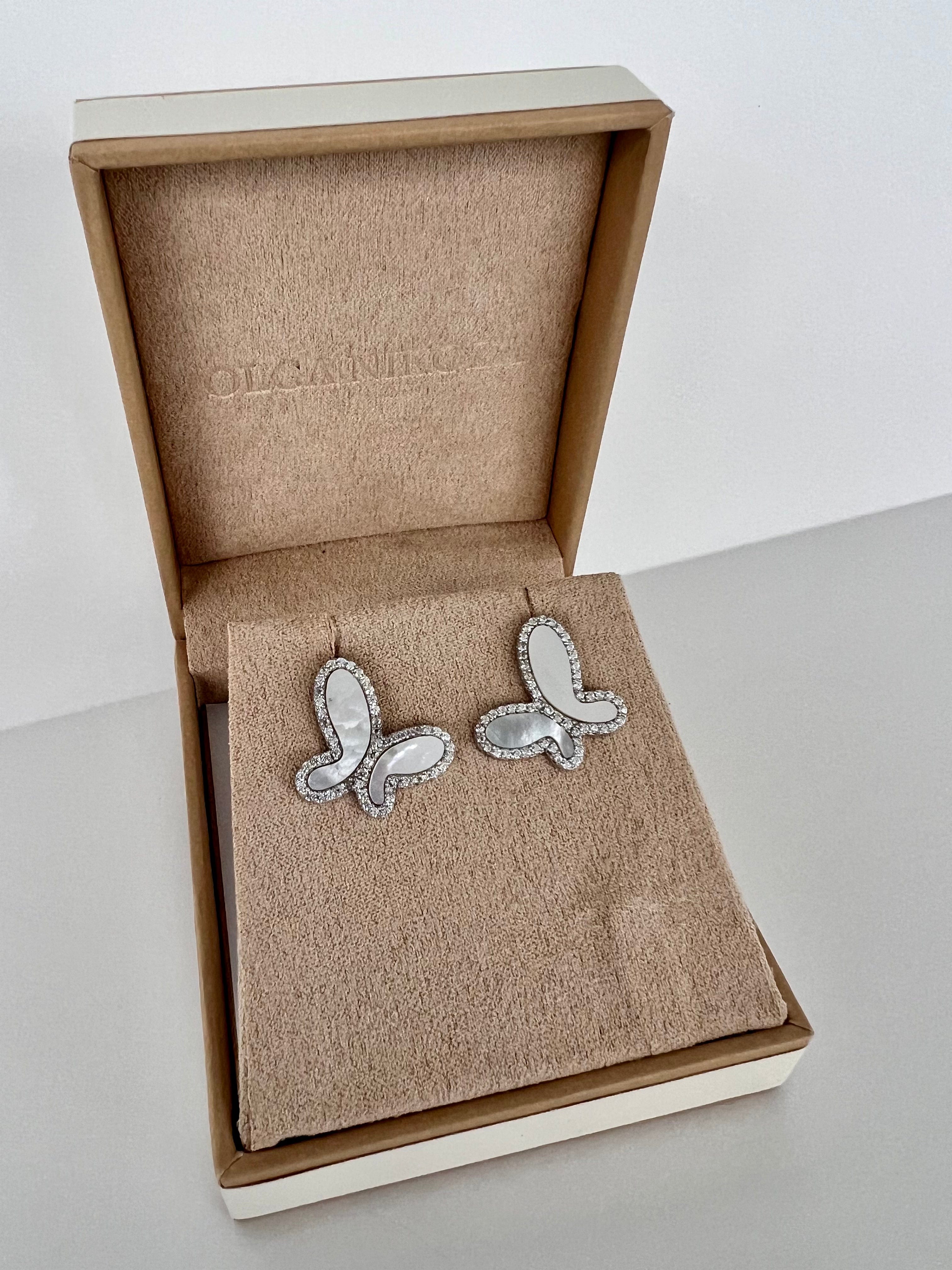 Butterfly-shaped earrings in a branded box on a light gray surface
