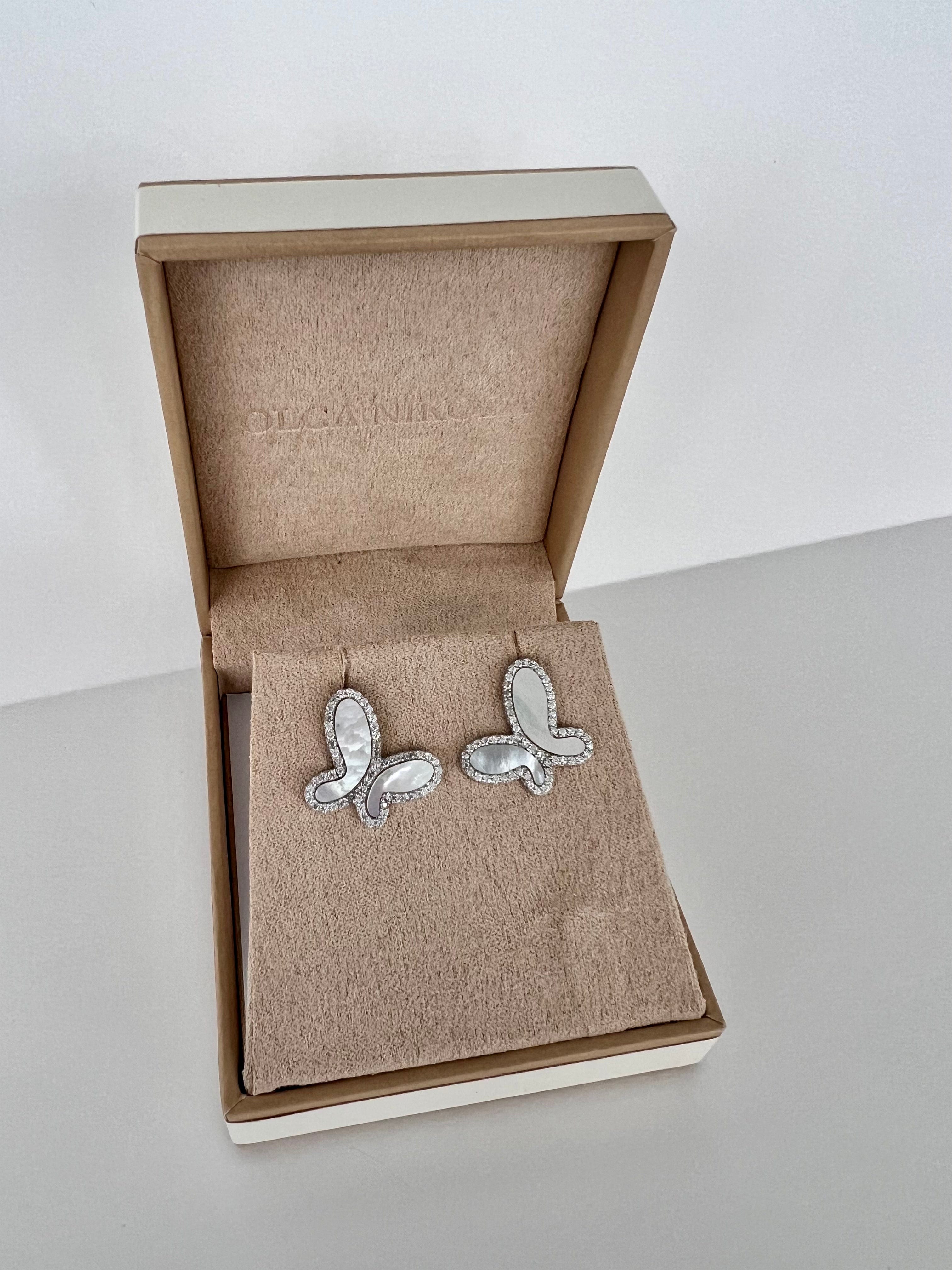Butterfly-shaped silver earrings in an open jewelry box on a light surface.