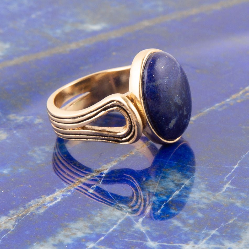 Gold ring with a blue stone on a blue marble surface