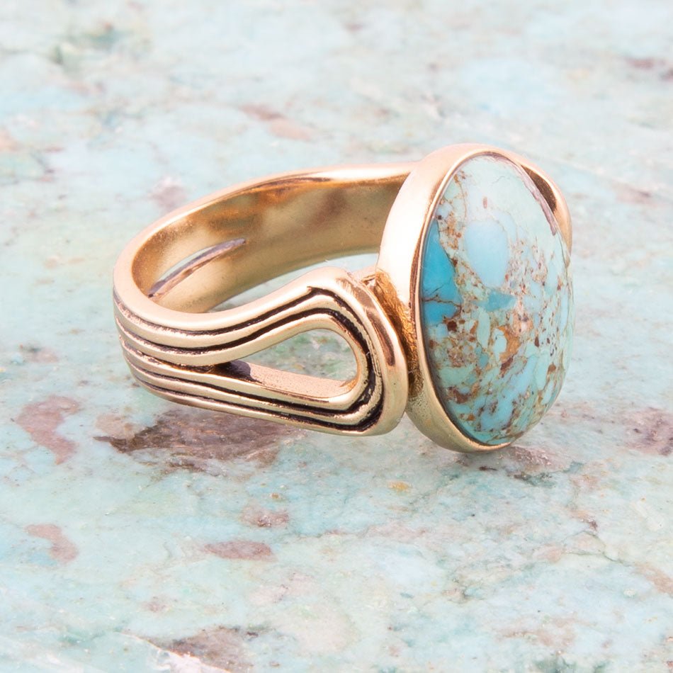 Gold ring with a turquoise stone on a textured surface