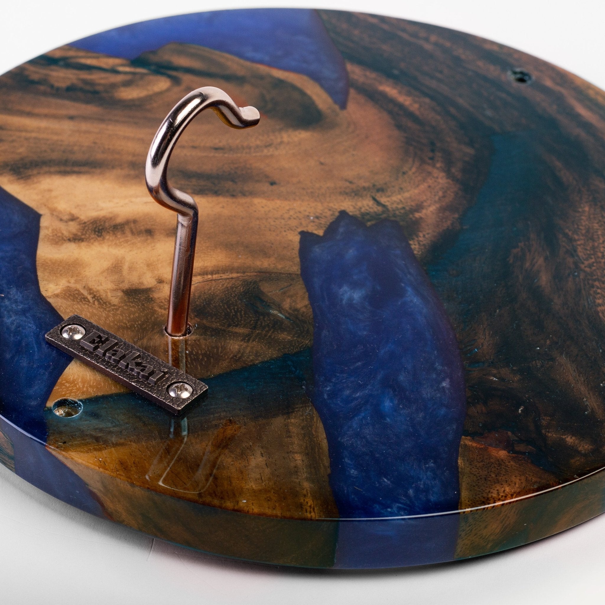 A close-up of a round wooden wall hook with a natural brown wood grain and blue resin inlay, featuring a silver metal hook and a small metal brand plate that reads 'MURPHY'.