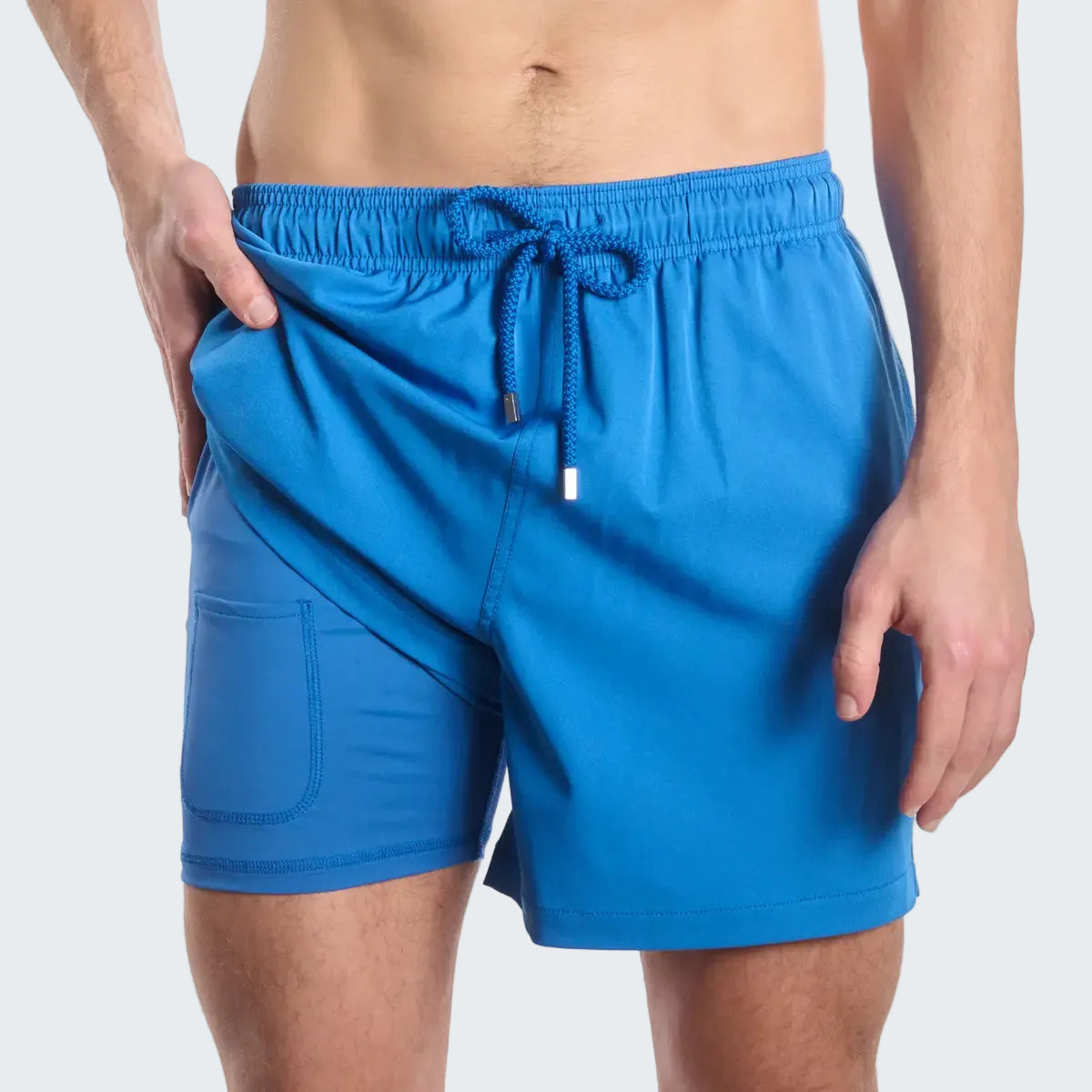 Blue swim shorts worn by a person on a white background