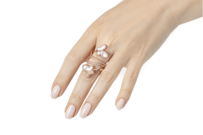Hand wearing multiple rings with a plain background