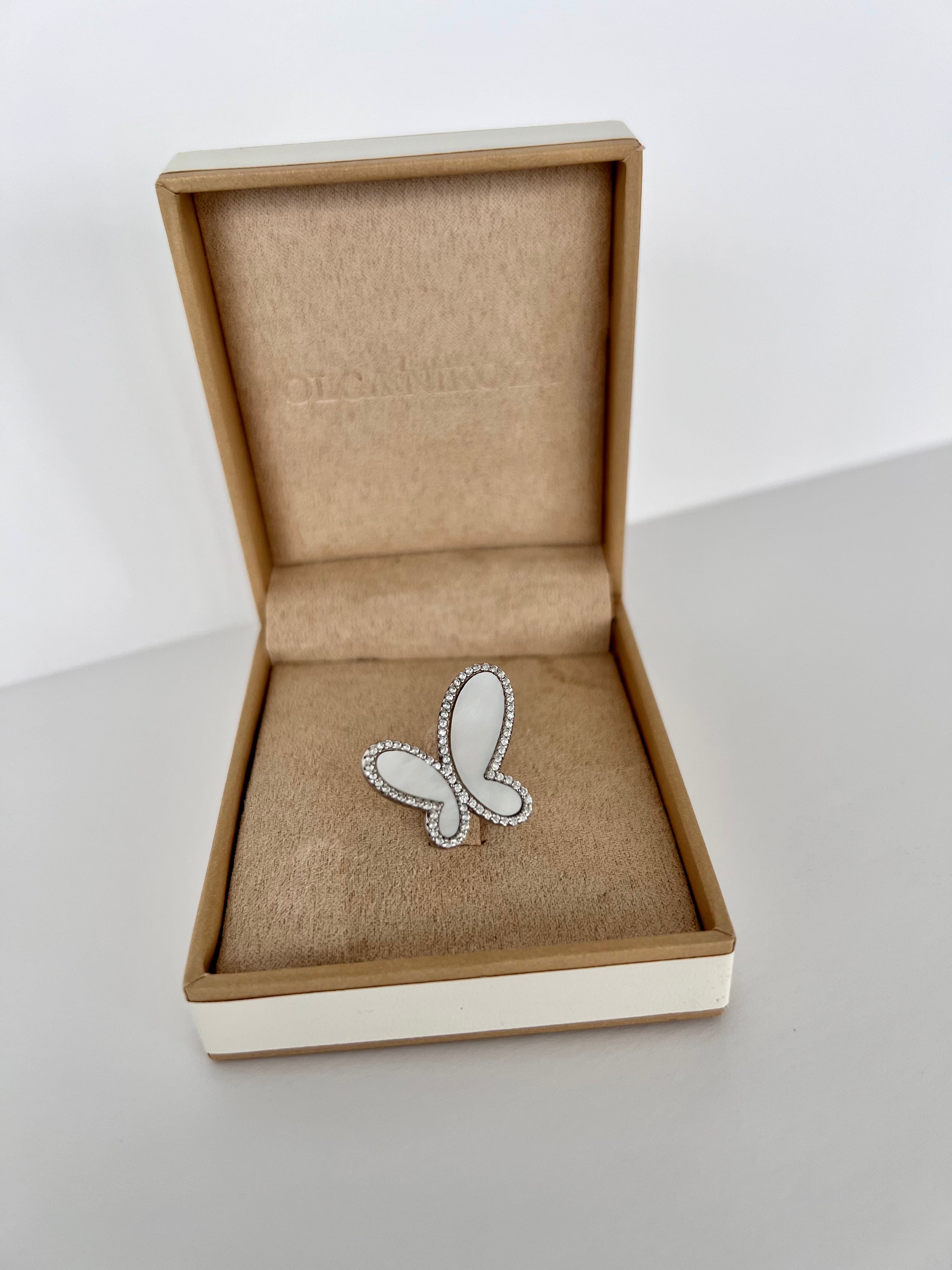 Butterfly-shaped brooch in an open jewelry box on a white surface