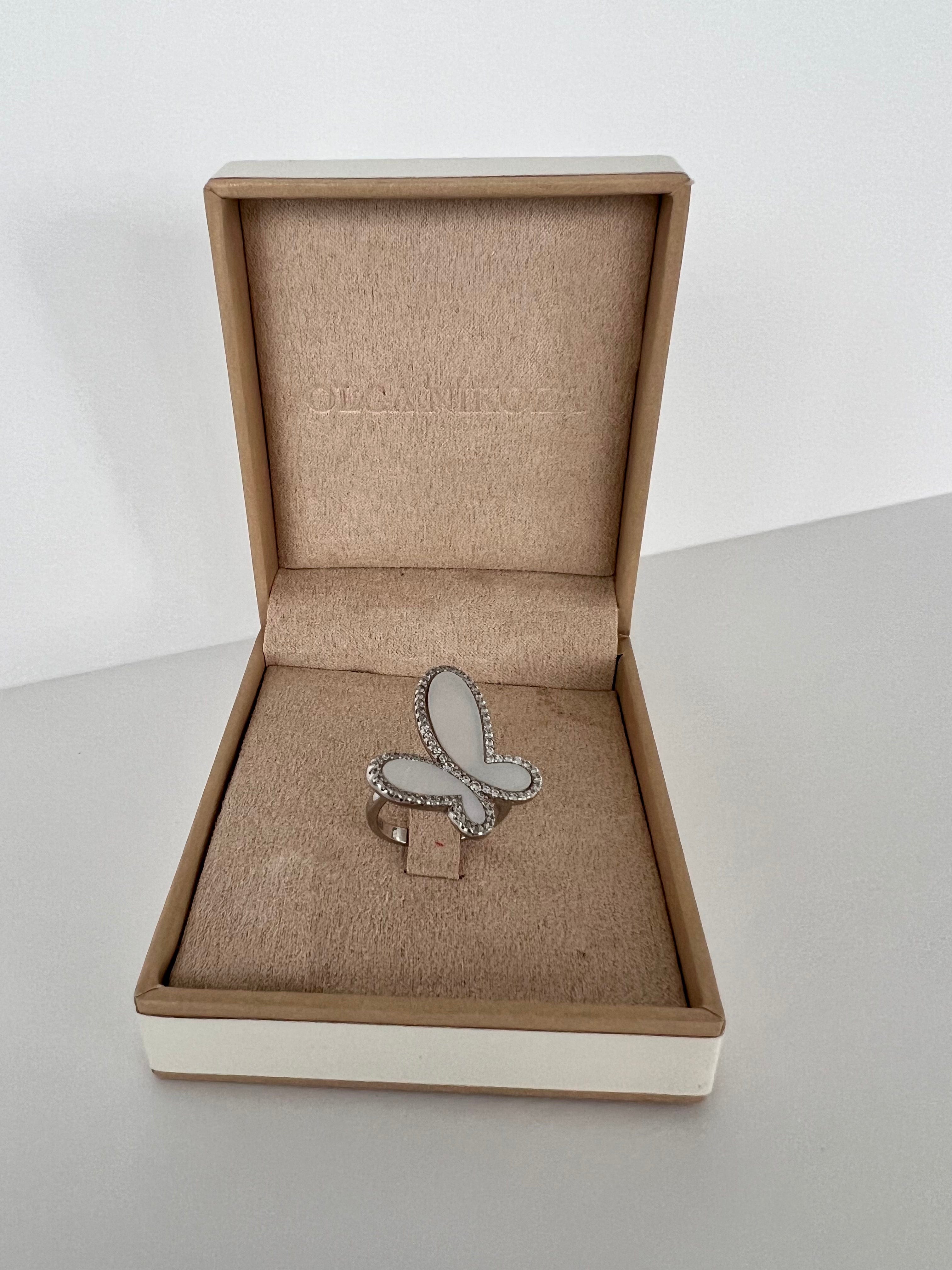Butterfly-shaped ring in a brown jewelry box on a light gray surface.