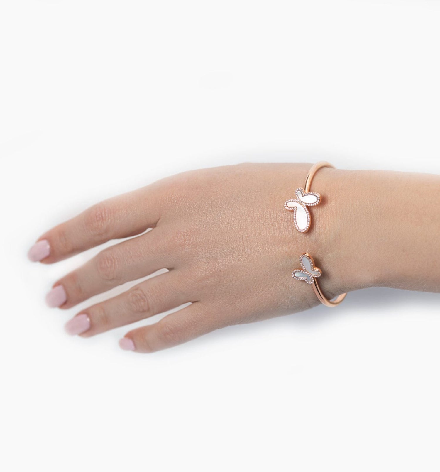 Hand wearing two rose gold bracelets with floral designs on a white background