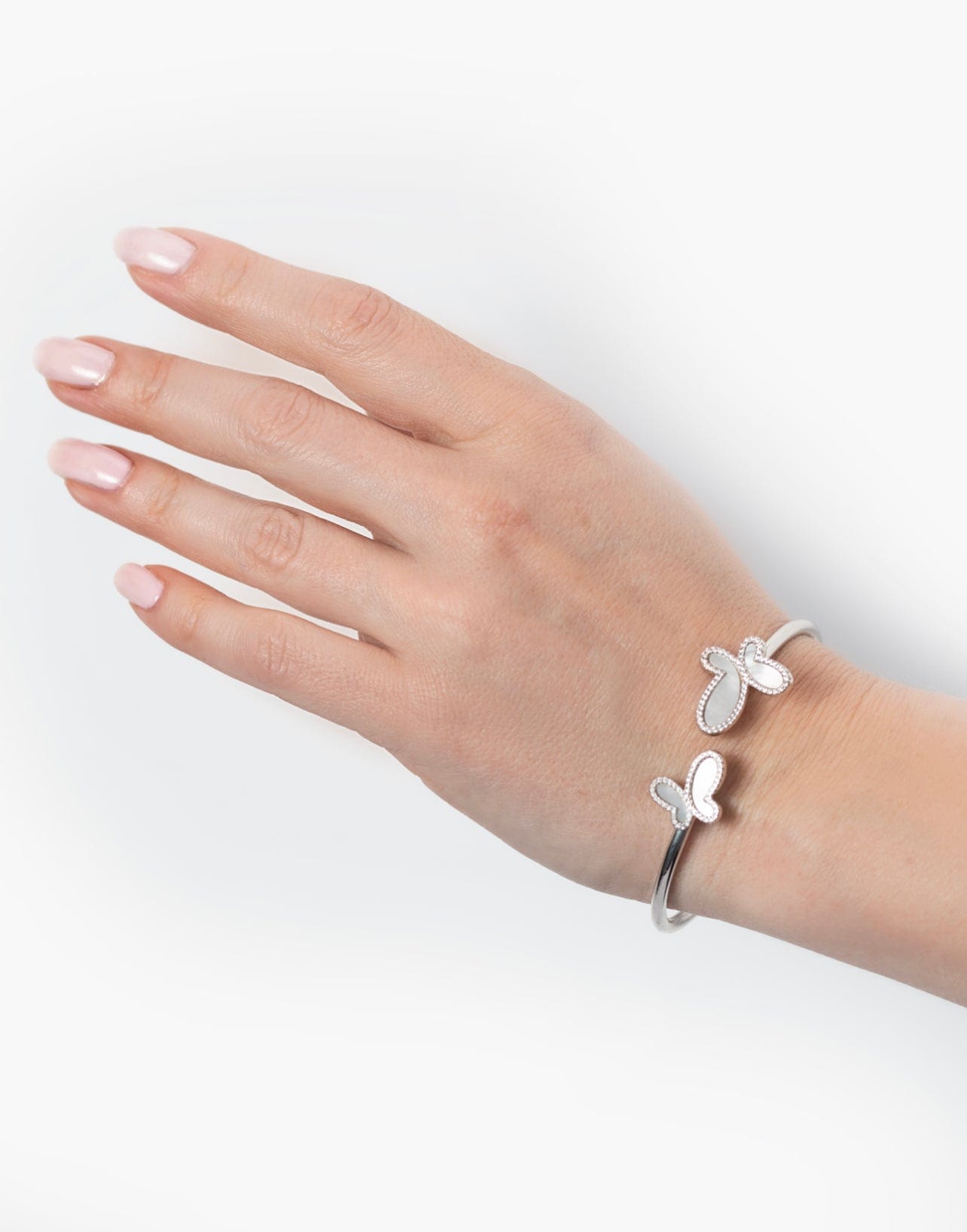 Hand wearing a silver butterfly bracelet on a white background