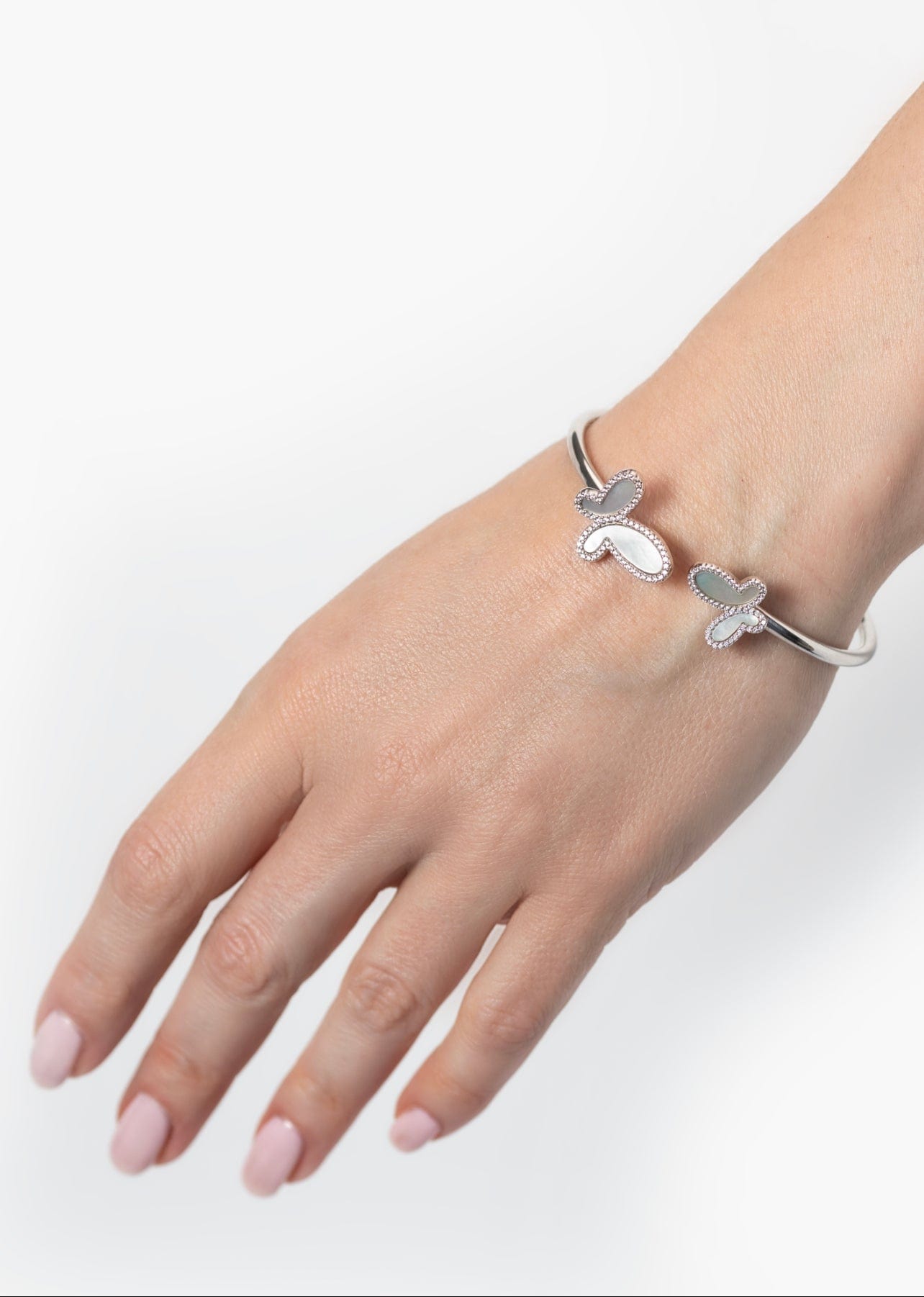 Silver bracelet with floral designs on a wrist against a white background