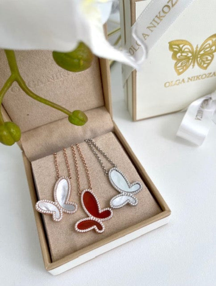 Butterfly-shaped necklaces in a box with a branded box in the background