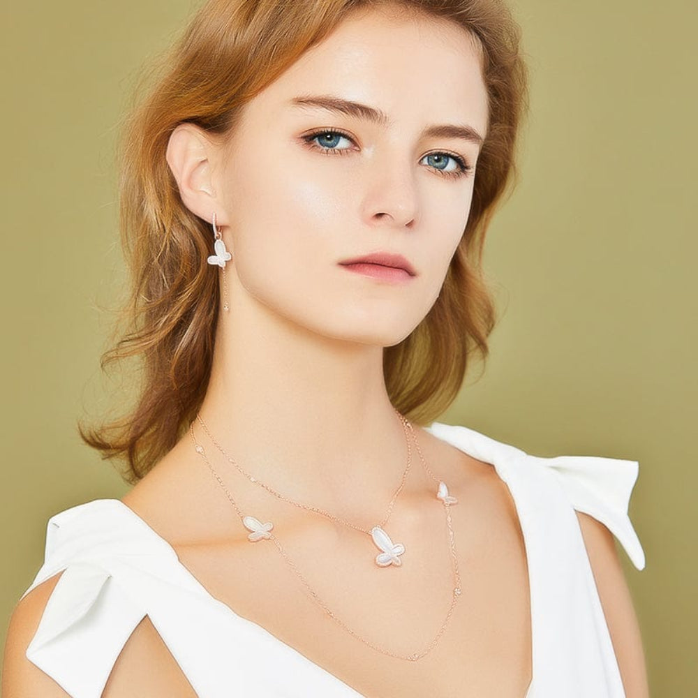 Woman wearing a delicate necklace with a plain background