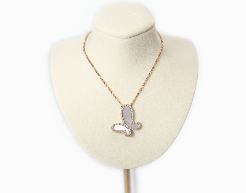 Butterfly pendant necklace on a mannequin bust with a white background