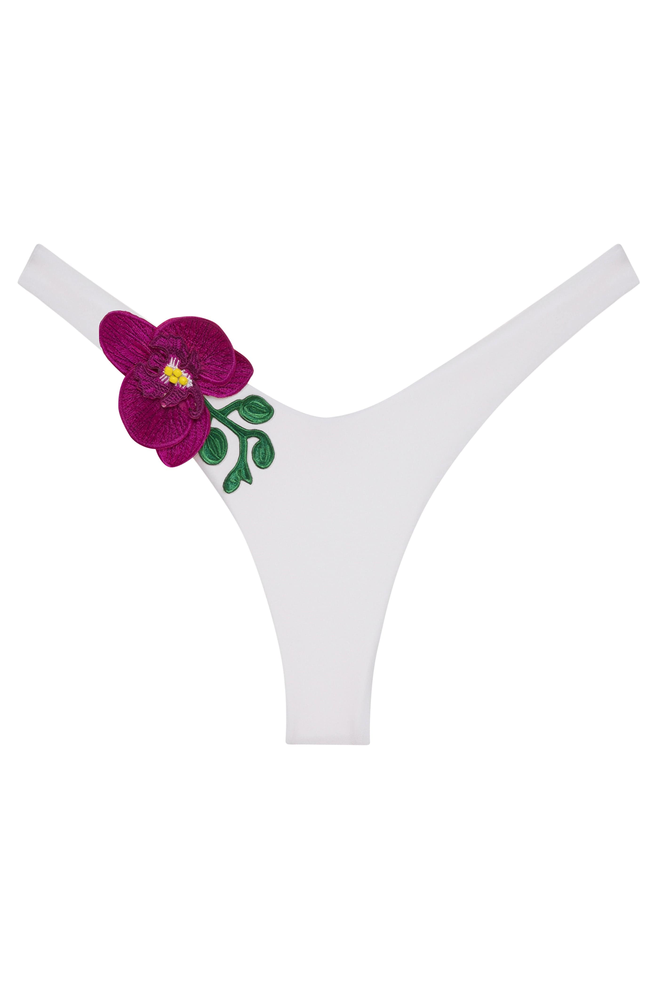 White thong underwear featuring a decorative embroidered magenta orchid flower with green leaves and a yellow center on the left hip, set against a plain white background.