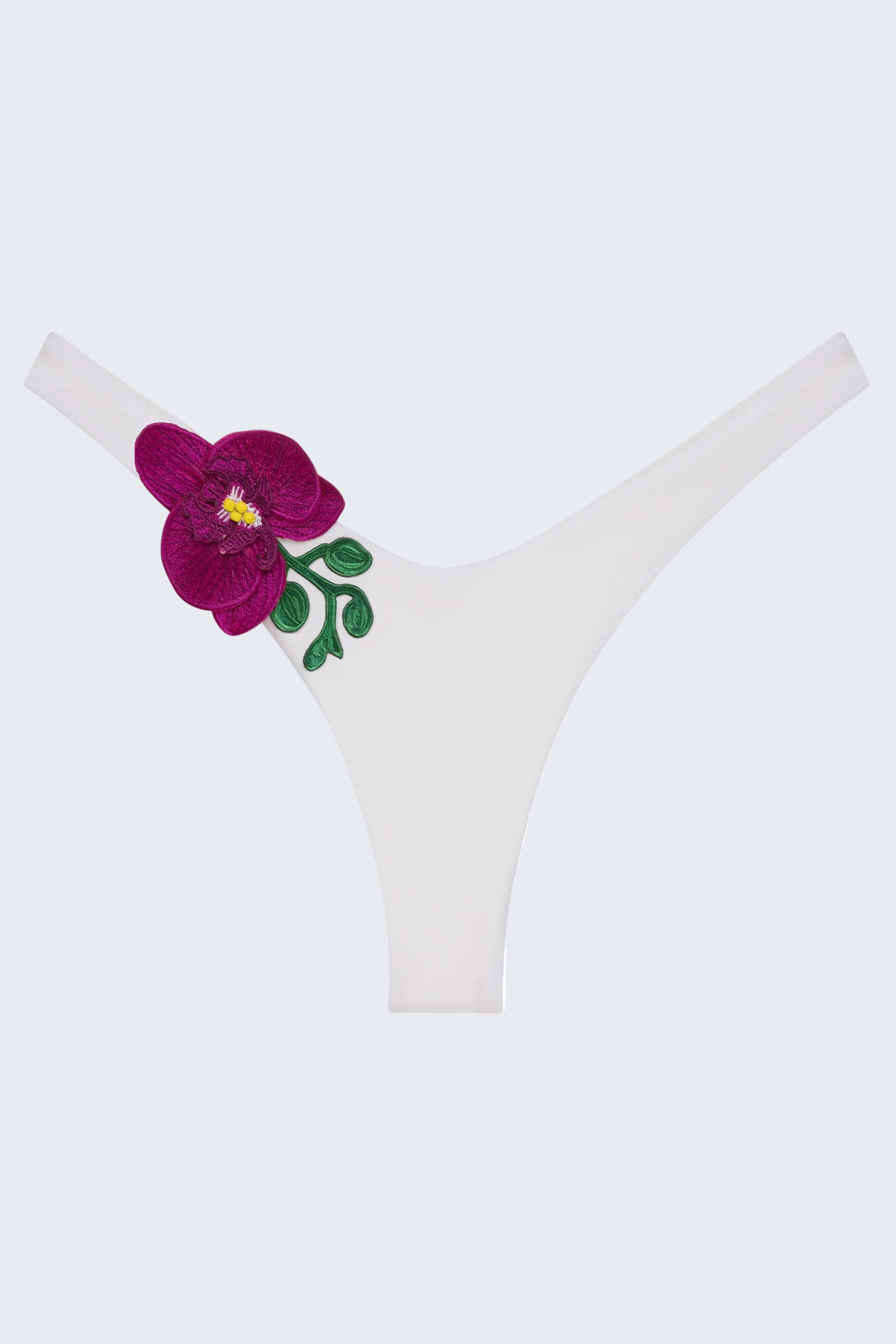 White thong underwear featuring a prominent embroidered magenta orchid flower with green leaves and a yellow center on the left side.