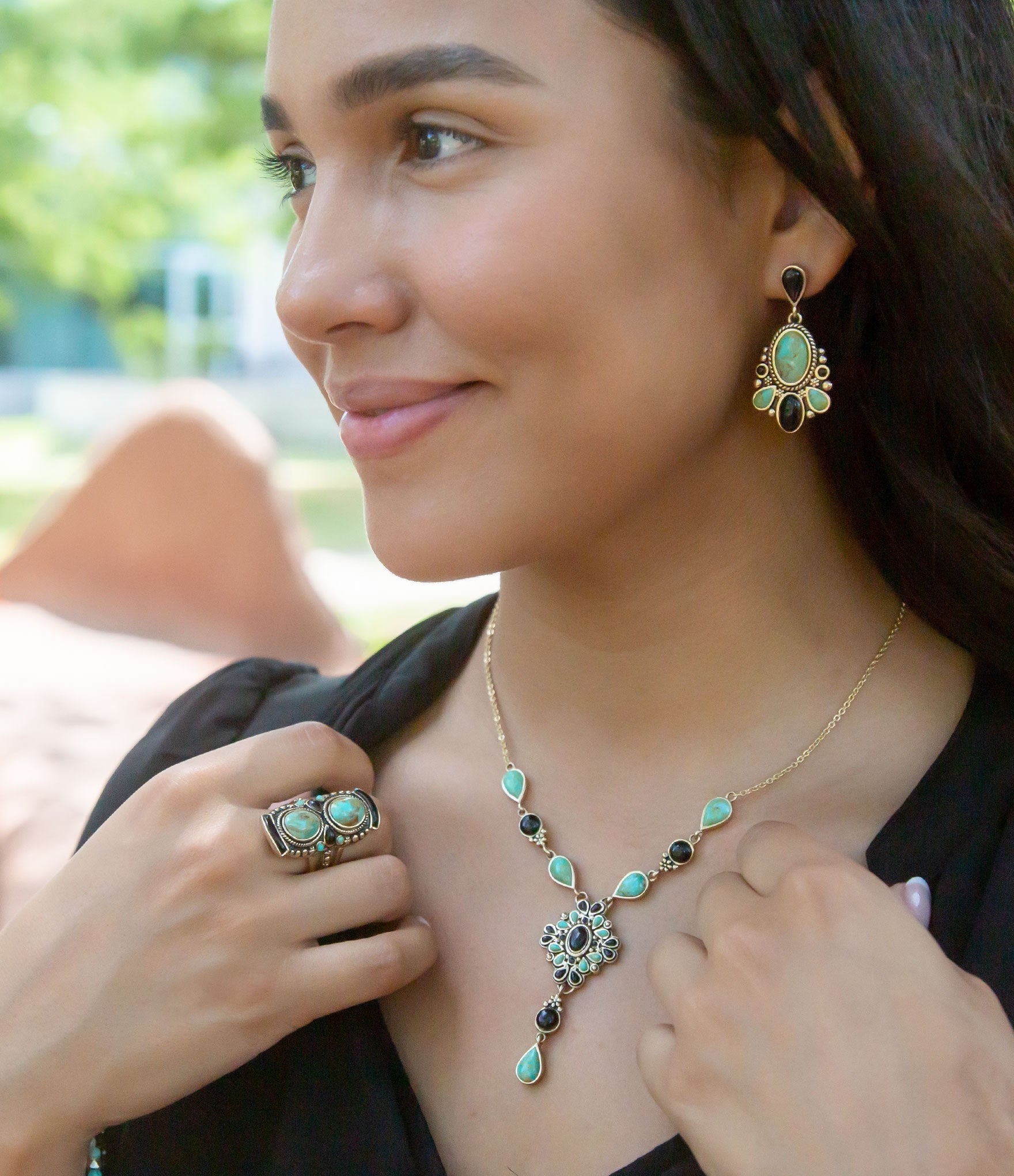 Woman wearing turquoise jewelry including a necklace and earrings outdoors.
