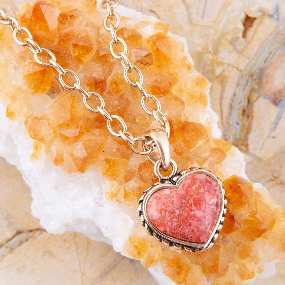 Necklace with a pink heart-shaped pendant on a rock background