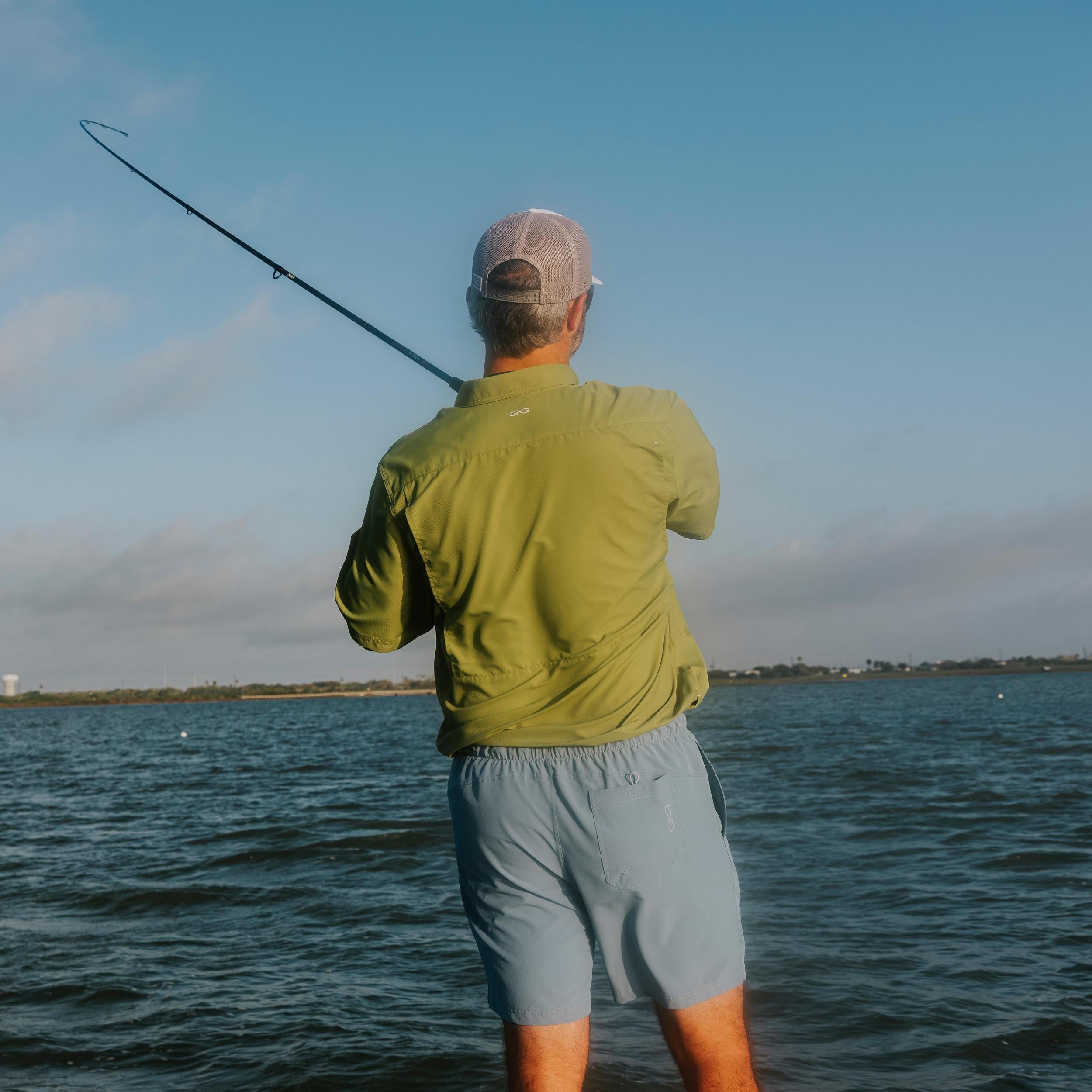 Man fishing in a body of water with a clear sky