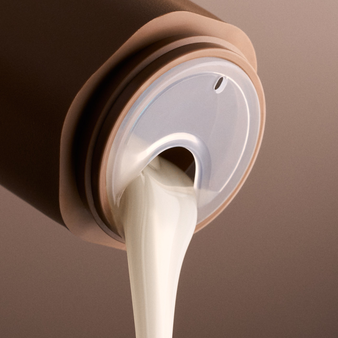 Brown container with a white liquid being poured out on a brown background