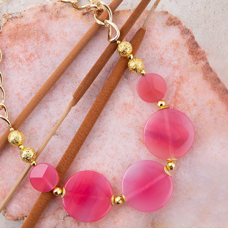 Bracelet with pink beads and gold accents on a pink stone background