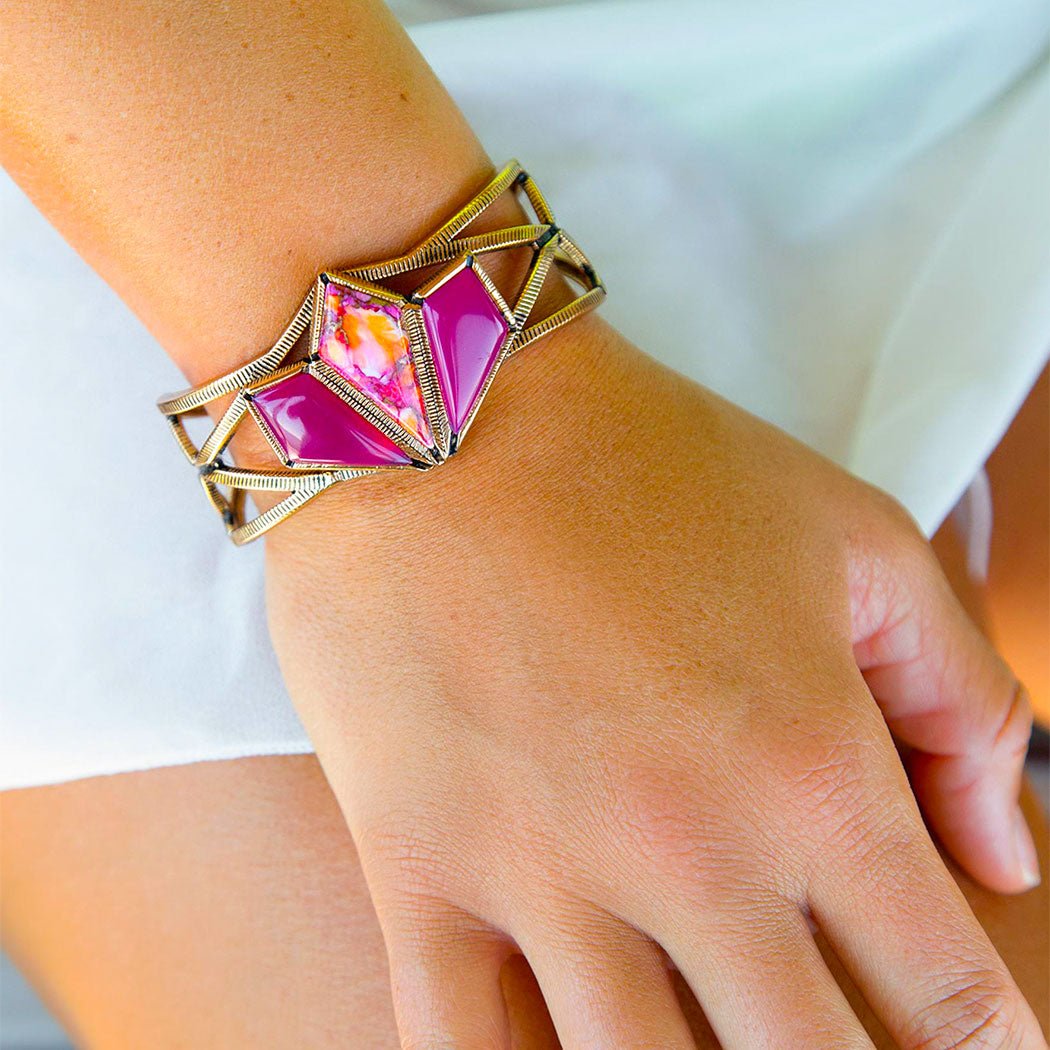 Close-up of a hand wearing a pink geometric bracelet on a white background